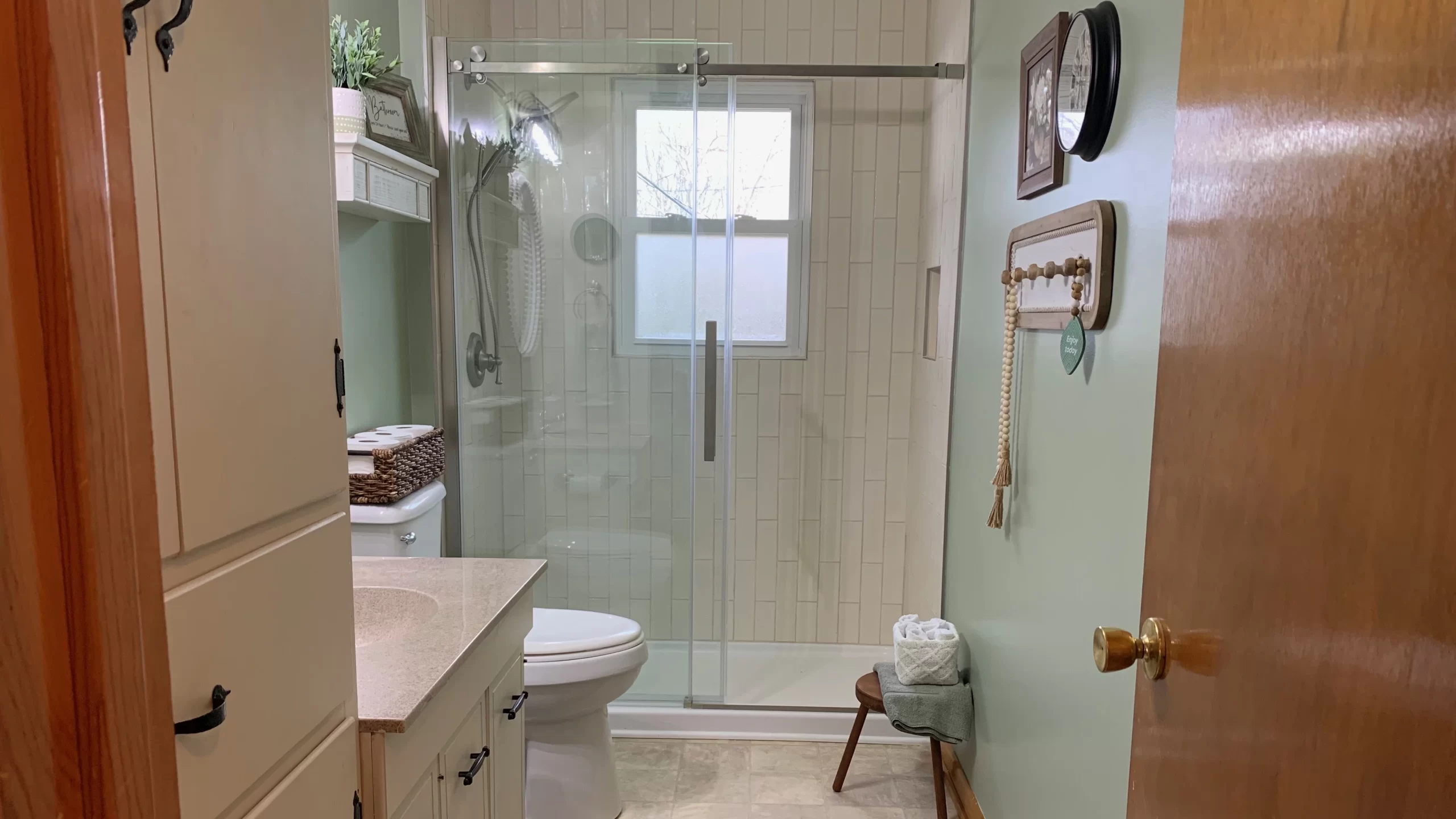 a completed bathroom renovation that has light green walls and a new tiled shower